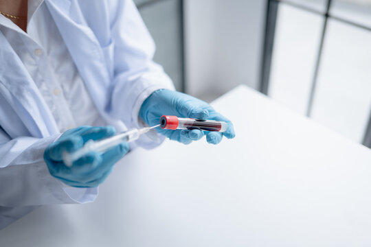 Female medical laboratory technician holding blood sample tube for laboratory testing at clinical laboratory.