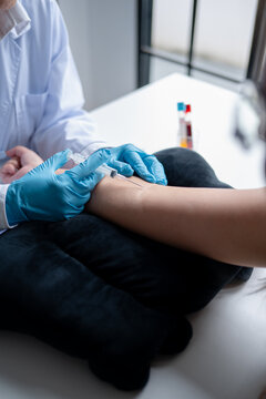 Female phlebotomist collecting blood sample from patient with needle for laboratory testing at medical clinic.