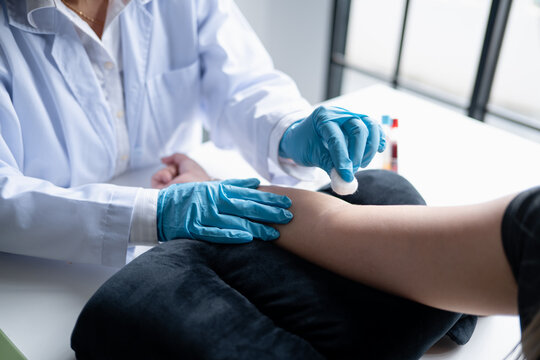 Female phlebotomist preparing equipment for blood draw during diagnostic testing at modern healthcare clinic.