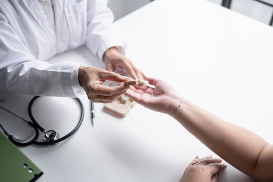 Doctor handing hearing aid to Asian female patient during hearing care consultation at medical clinic