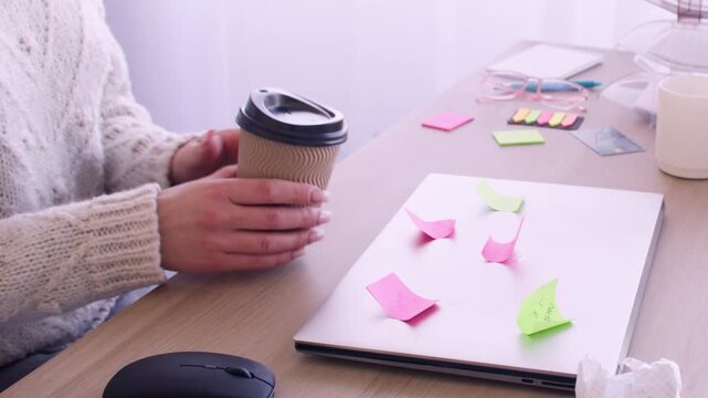 Distance job. Office worker. Unrecognizable secretary female drinking coffee at professional workplace desk with laptop indoor.