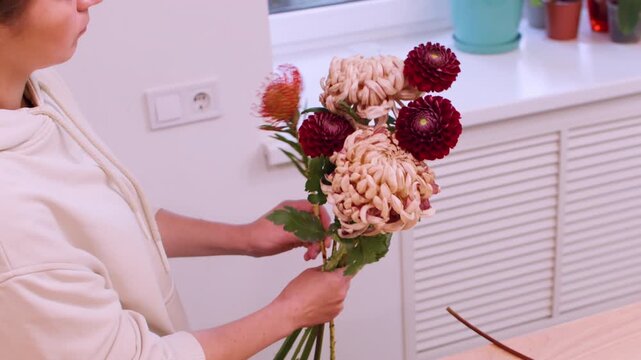 Bloom bouquet. Exotic floristry. Professional female floral designer arranging autumn color chrysanthemum flowers in workshop.