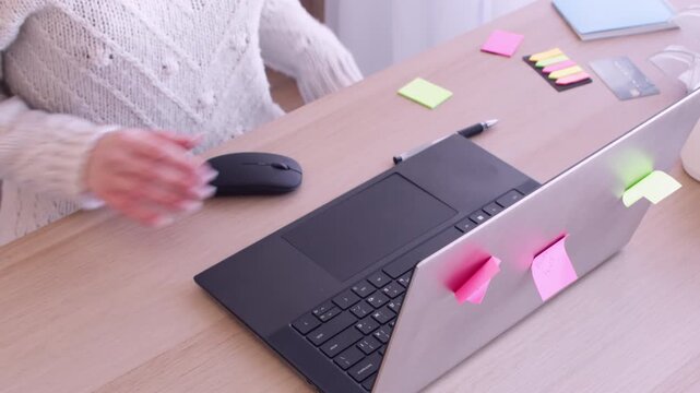 Woman employee. Office routine. Unrecognizable entrepreneur writing in notebook at desk with laptop sticky notes for professional occupation.
