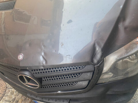 Mercedes Benz Sprinter van showing front end collision damage, dented hood and broken headlight