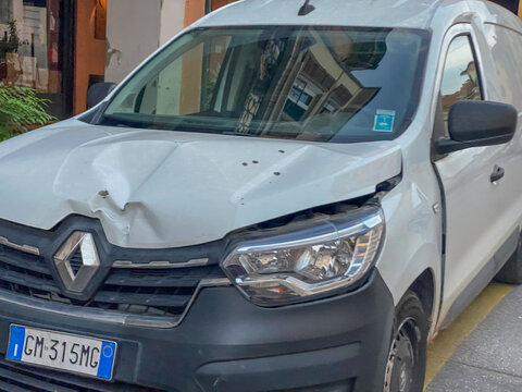 White Renault Kangoo delivery van with a damaged hood and headlight after a car collision on a city street