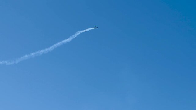 Stunt Plane Performing Aerobatics with Smoke Trail in Blue Sky