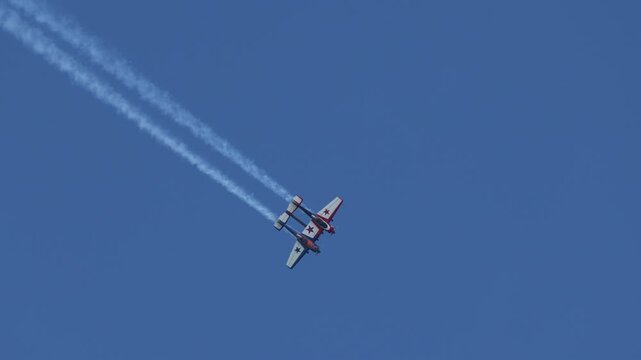 Aerobatic Stunt Plane Leaving Smoke Trails Across Blue Sky