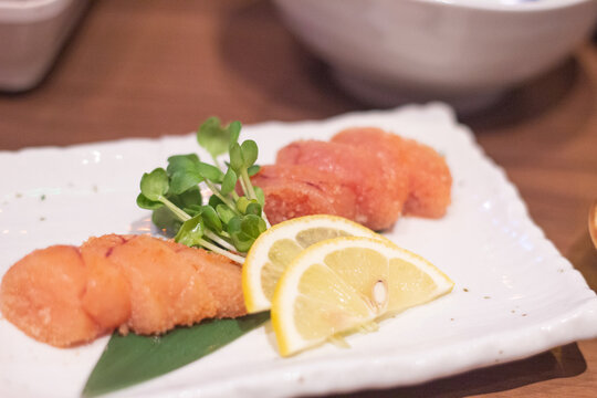 Top down view of spicy cod roe or mentaiko served with sliced lemon in a white plate. Kumamoto, Kyushu, Japan