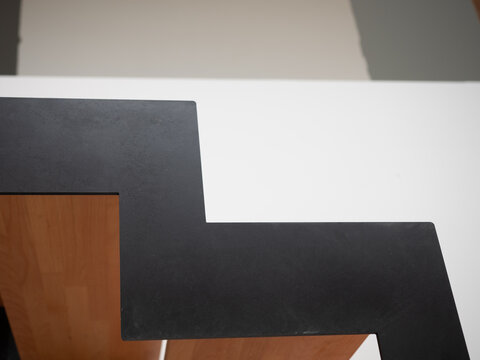 Side view of a modern staircase with black metal zigzag stringer and wooden steps, showing structural detail, geometric design and contemporary interior construction.