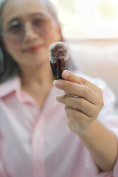 Close-up shot of mature Asian woman's hand holding a wireless lavalier microphone