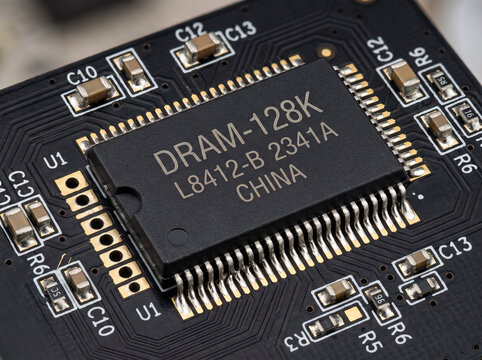 Dram 128k memory chip mounted on black printed circuit board with ceramic capacitors near.