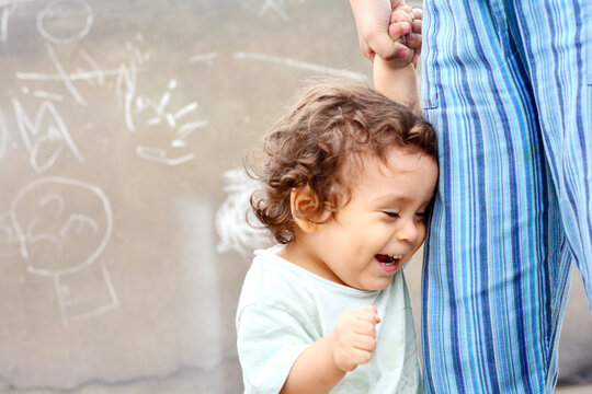 Laughing toddler holds his mommy's hand.