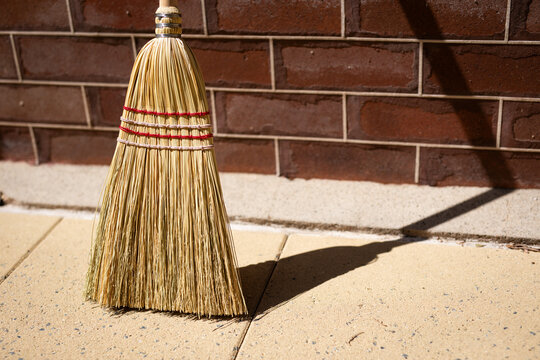 Traditional Broom Leaning Against Brick Wall