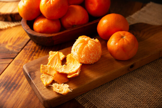Mandarin Orange fresh fruit. Peeled organic mandarin orange with peels on a wooden cutting board, showcasing a fresh and healthy snack option.