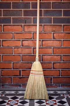 Wooden Broom Against Brick Wall Background