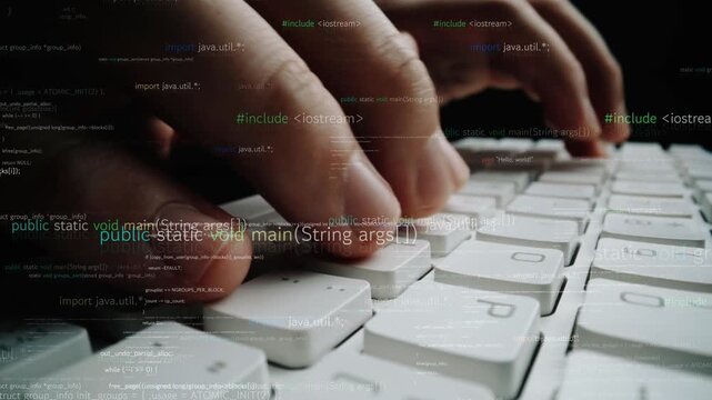 Close-up view of hands typing on a computer keyboard with programming code and elements in the background, representing technology and coding environments. Xenic