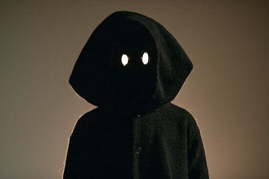 Eerie shadow monster costume with a dark oversized hood and glowing abstract eyes for Halloween