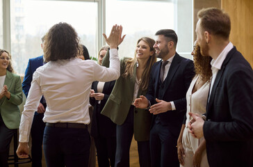 Naklejka premium Business team success celebration with highfive. Employees in a modern office share a high five, smiling and happy about achievement today. Positive teamwork unity and motivation concept.
