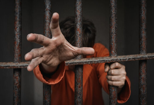 Hand grips rusted bars, fingers spread in desperation