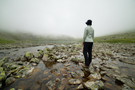 Female Person Standing on Submerged Rocks near Misty Lake Landscape