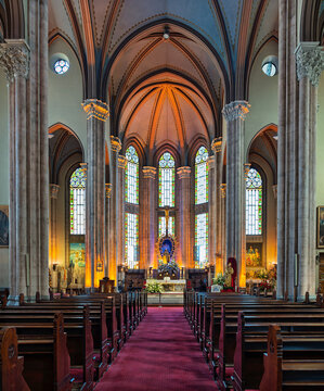 Interior of the ornate St Anthony of Padua Church in Istanbul, Turkey, featuring Gothic architecture, stained glass windows, wooden pews, and a red carpet aisle leading towards the altar