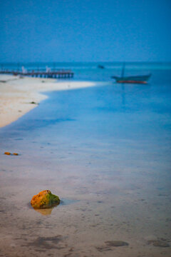 Old fisher boat in the shore of a quiet white sand beach at dusk in Maldives