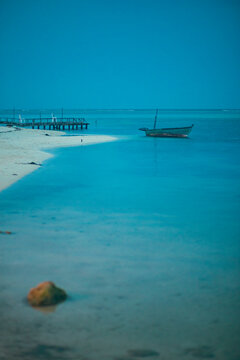Old fisher boat in the shore of a quiet white sand beach at dusk in Maldives