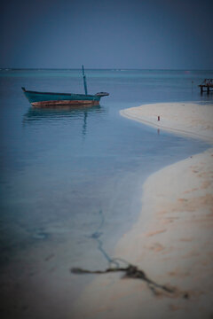 Old fisher boat in the shore of a quiet white sand beach at dusk in Maldives