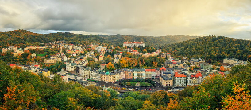 Karlovy Vary, Czechia - 11.10.2024: Panoramic view of historic spa town architecture and autumn foliage in a valley under a cloudy sky
