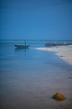 Old fisher boat in the shore of a quiet white sand beach at dusk in Maldives