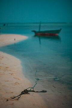 Old fisher boat in the shore of a quiet white sand beach at dusk in Maldives