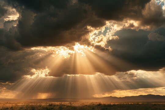 Golden sun rays breaking through dark clouds illuminating a vast field at sunset