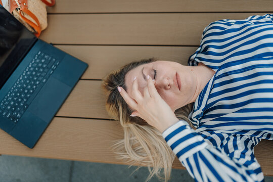 Woman experiencing burnout while working remotely outdoors