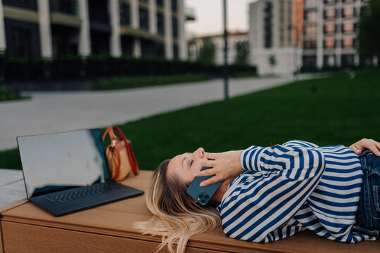 Woman relaxing outdoors making phone call on smartphone