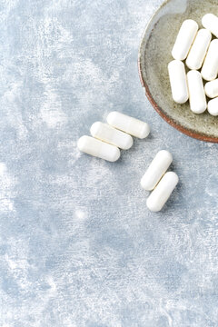 Creatine capsules on wooden background. Soft focus. Close up. Copy space