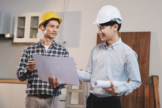 Asian architect and engineer team checking architectural house model using measuring tape on the table at office studio.
