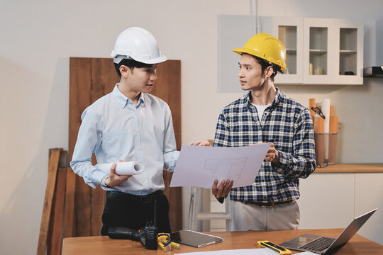 Asian architect and engineer team checking architectural house model using measuring tape on the table at office studio.