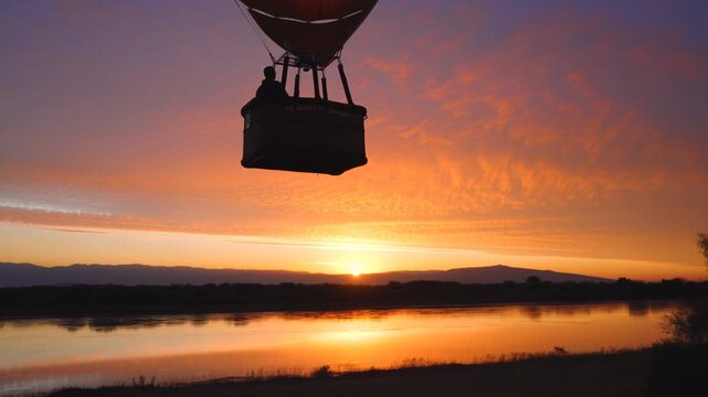 A breathtaking hot air balloon floats serenely over a tranquil lake, capturing the vibrant colors of a stunning sunset reflected on the water's surface.