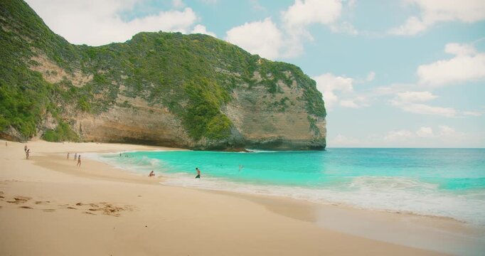 Tourists relax on a tropical white sand beach in Nusa Penida Island Bali