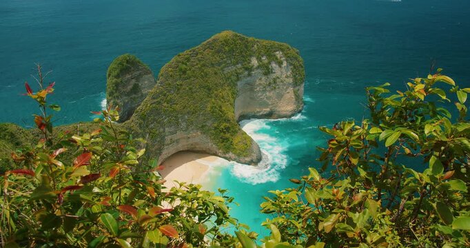 Sandy cove and turquoise surf beneath steep cliffs at Kelingking Beach Nusa Penida Bali