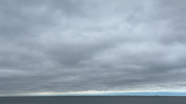厚い雲に覆われた曇り空と水平線に浮かぶ船