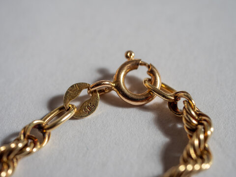 Macro close-up of a gold chain clasp with 585 hallmark indicating 58.5% gold purity, equivalent to 14 karat gold, showing jewelry fastening and metal craftsmanship.