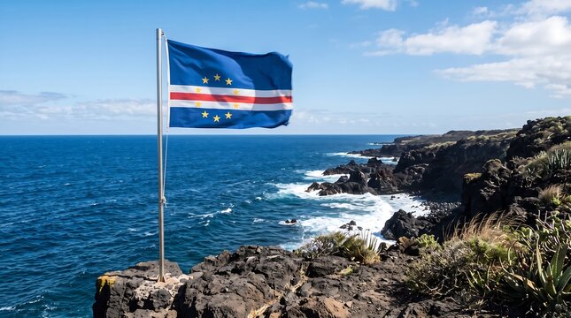 National flag of Cape Verde waving on pole atop rocky coastal cliff overlooking blue Atlantic Ocean