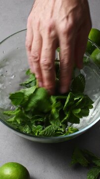 Close side view shows hand cooling wilted mint in ice water to restore freshness for summer drinks.
