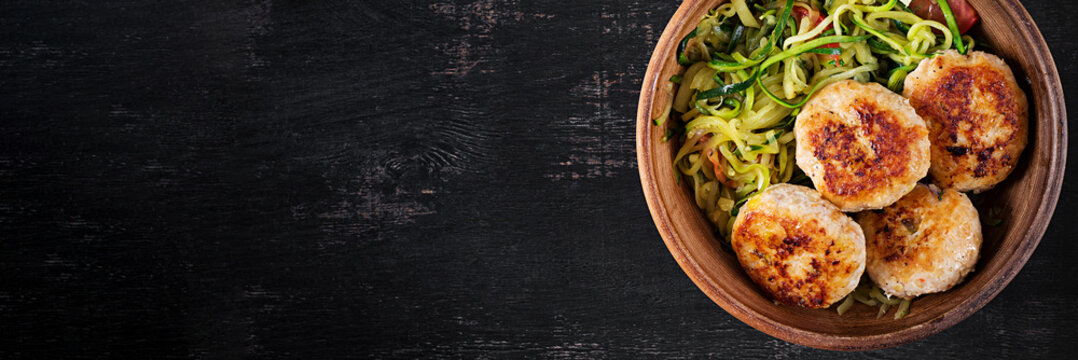 Zucchini spaghetti pasta  with chicken meatballs in bowl. Top view. Banner
