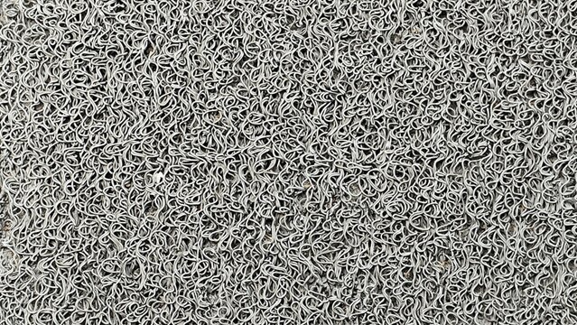 Full-frame top-down close-up of a grey PVC coil mat, also known as a noodle mat.