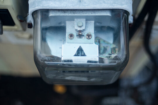 Close up of analog electricity meter measuring power consumption.A high-quality close-up shot focusing on an outdoor analog electricity meter (kilowatt-hour meter) protected by a dusty glass 
