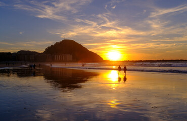 Obraz premium Golden Sunset Over Zurriola Beach and Ocean Waves in San Sebastian