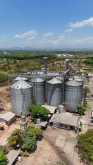 Large industrial grain silos for agricultural crop storage seen from a high drone perspective © Salsabila Ariadina