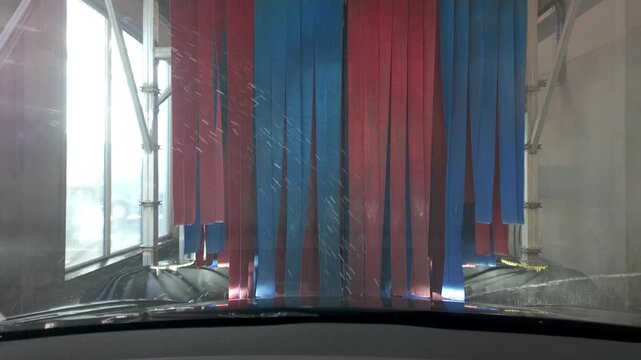 POV Footage of a Vehicle in an Automated Car Wash with Water and Foam on the Windscreen